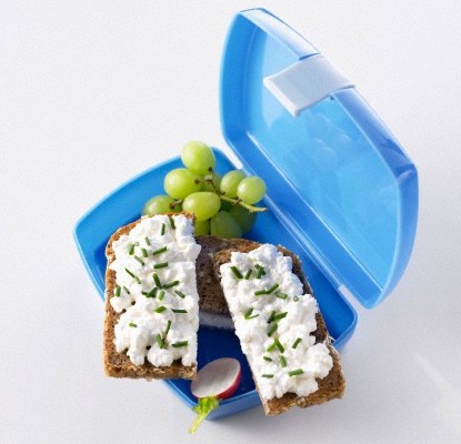 Lunch box with soft cheese sandwiches, grapes and radish